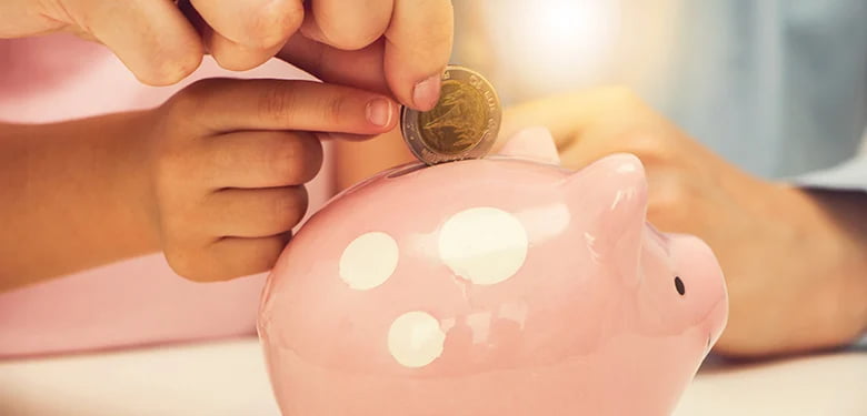 Image of child putting coin into piggy bank